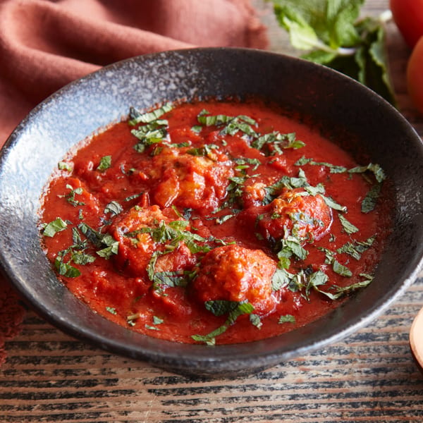 A black bowl of Kasa Indian Eatery's chicken tikka masala, garnished with fresh herbs.