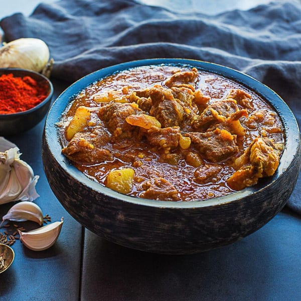A bowl of Kasa Indian Eatery's rich, savory lamb curry with potatoes, spices, and garlic.