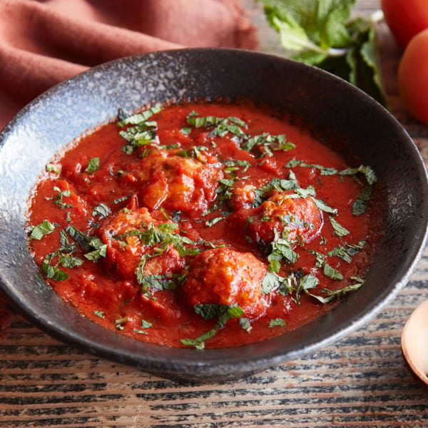 Kasa Indian Eatery's chicken tikka masala, a rich red curry with chicken pieces, garnished with fresh herbs.